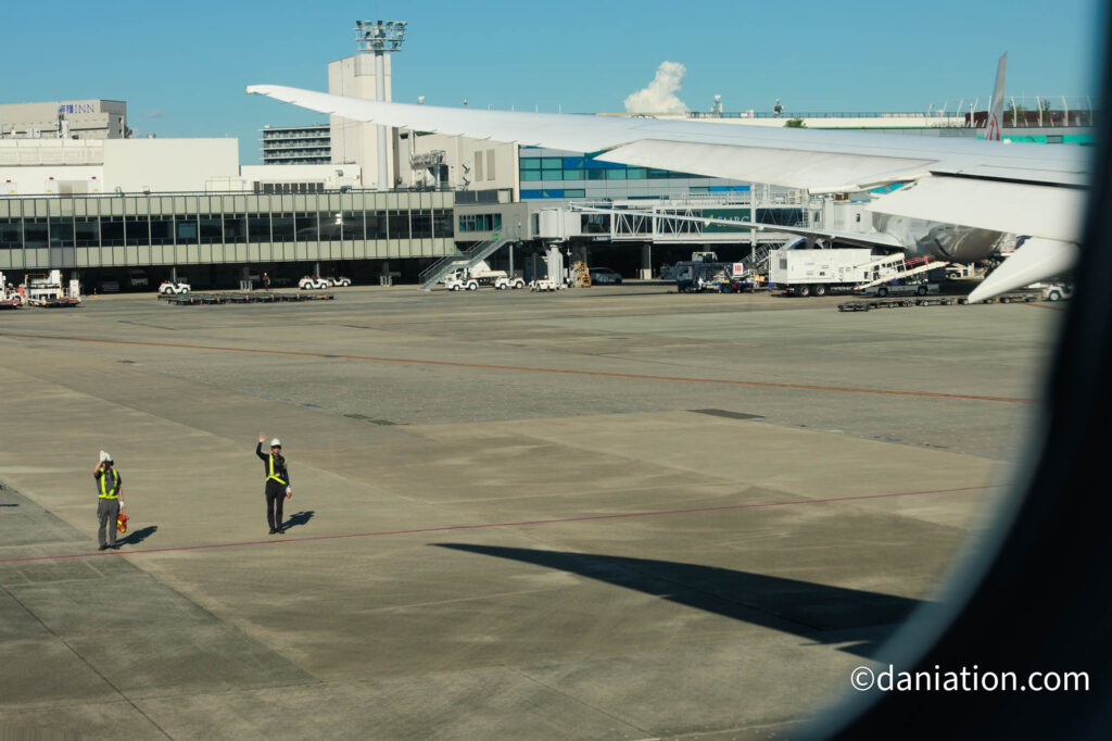 手を振るグランドハンドリングのスタッフとJAL B787の翼。